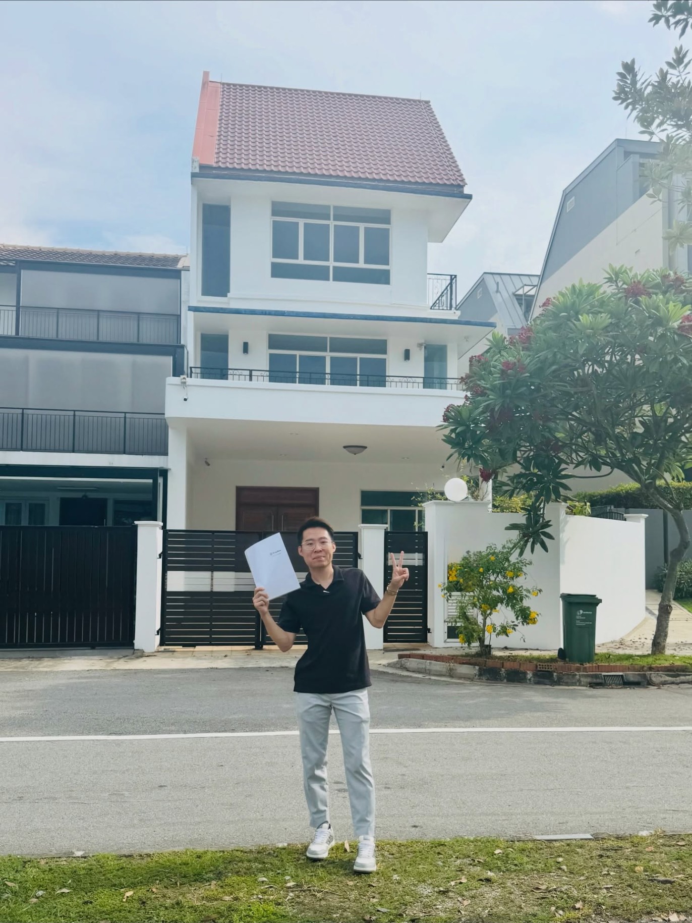 Nigel Aw holding a signed sale agreement outside a landed home in the East Coast